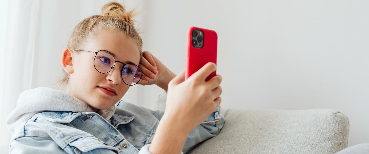 Kinderaugen schützen: EIn junges Mädchen schaut in ihr Smartphone. Sie trägt eine Brille.